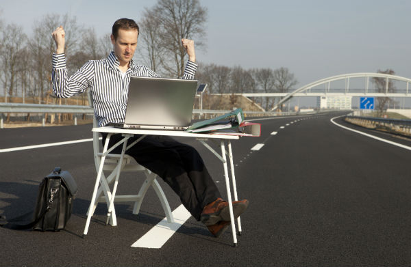 Businessman with laptop on a highway