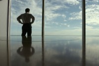 Businessman looking outside window with clouds