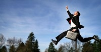Businessman holding suitcase jumping high
