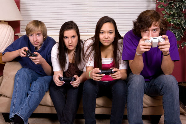 Four serious looking teenagers playing a video game
