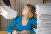 Woman on a desk receiving stacks of papers for work