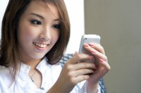 Asian woman happily looking at her mobile phone