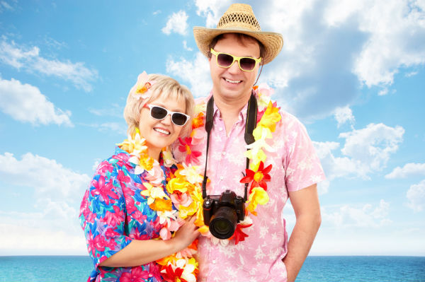 A tourist couple smiling with a beach scenery behind