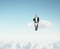 Businessman sitting on a cloud while drinking his coffee