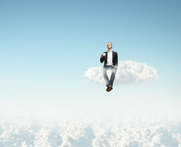 Businessman sitting on a cloud while drinking his coffee
